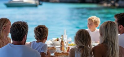enjoying a lunch aboard of a small motor yacht anchored on a white sand and clear water bay. The table is setup cozy and fresh.